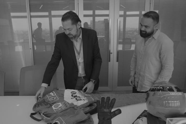 Macacão, luvas e capacete de Fórmula 1 sobre a mesa, na entrega ao CEO da Capgemini